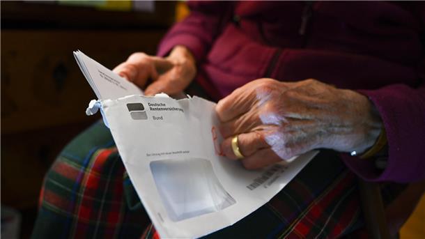Eine Seniorin hält ihren Rentenbescheid in der Hand.