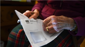 Eine Seniorin hält ihren Rentenbescheid in der Hand.