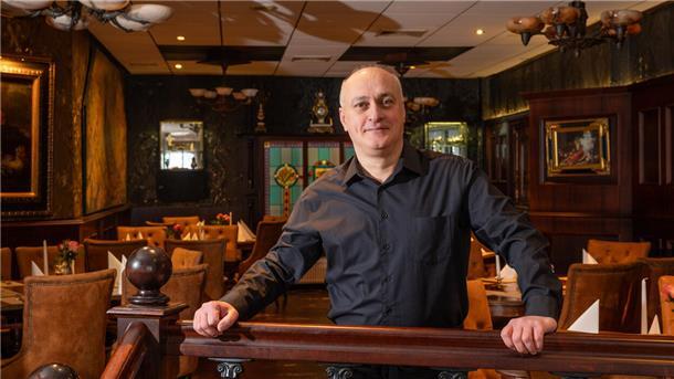 Ein Mann steht in einem Restaurant und lehnt an einem Geländer