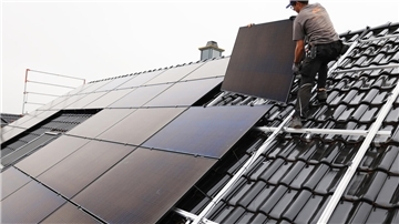 Handwerker montieren auf dem Dach eines Wohnhauses Solarmodule.
