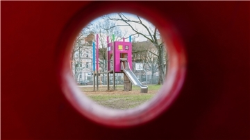 Blick durch ein Schaukelpferd auf eine Rutsche auf einem Kinderspielplatz.