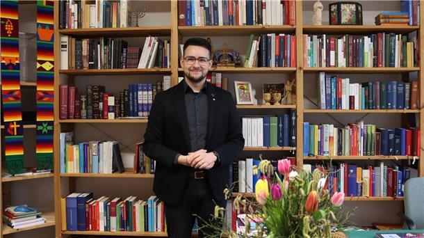 Glaube, Liebe, Hoffnung: Heiner Georgi-Gerdes als neuer Pastor in Zeven Mann in Anzug vor Bücherregal