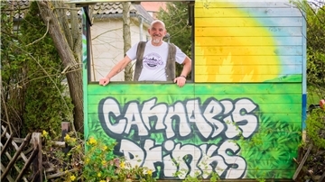 Heinrich Wieker vom Cannabis Socialclub Hannover e.V. an seinem Gartenzaun an einer Bretterbude.