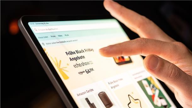 Eine Person schaut sich die Black Friday Angebote auf der Online-Shopping-Seite von Amazon auf seinem Tablet-Computer an. 