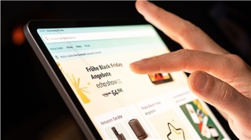 Eine Person schaut sich die Black Friday Angebote auf der Online-Shopping-Seite von Amazon auf seinem Tablet-Computer an. 