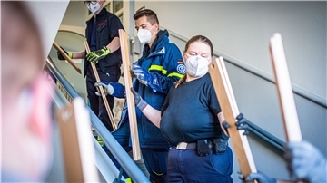 Helfende Hände übergeben einzelne Lattenrostteile vom Erdgeschoss bis in die erste Etage, dort wo aus den Einzelteilen ganze Betten für die Geflüchteten zusammengebaut werden sollen.
