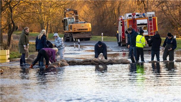 Sperrungen, Evakuierungen: Hochwasserlage bleibt angespannt Helfer bauen mit Sandsäcken einen Deich auf einer Straße im thüringischen Windehausen.