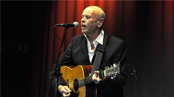 Helmut Debus in Brake: Altes Herz voller Poesie Mann mit Gitarre steht an einem Mikrofon und singt.