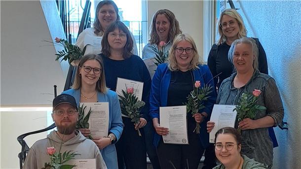 Diese Frauen und Männer unterstützen bald die Kitas in der Wesermarsch Das Foto zeigt mehrere Männer und Frauen, die auf einer Treppe stehen und Zertifikate in den Händen halten.