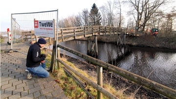 Ein Mann stellt eine Absperrung vor einer Holzbrücke auf. Die alte Holzbrücke an der Seebeckstraße in Bad Bederkesa soll abgerissen werden.