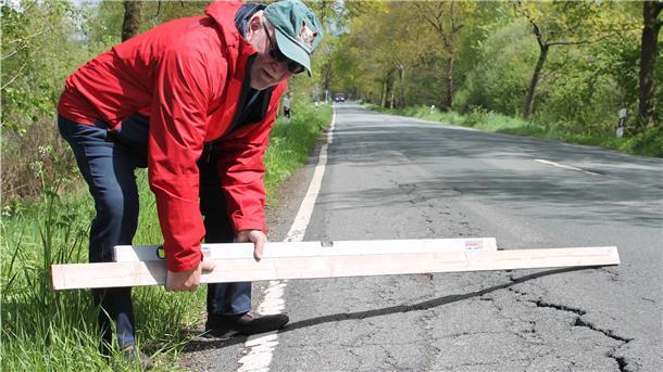 Hier geht’s bergab: Mit der Wasserwaage zeigt Kurt Grosshans das Gefälle an manchen Stellen der Landesstraße 128 zwischen Wollingst und Osterndorf.