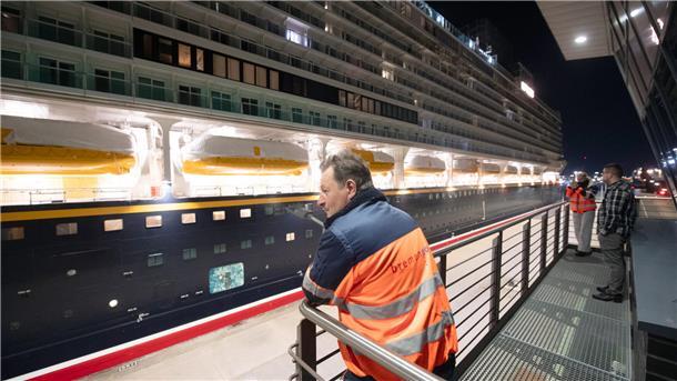 Ein Mann steht an einem Geländer. Vor ihm wird das Kreuzfahrtschiff "Disney Adventure" durch die Kasierschleuse in Bremerhaven geschleust.