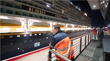 Ein Mann steht an einem Geländer. Vor ihm wird das Kreuzfahrtschiff "Disney Adventure" durch die Kasierschleuse in Bremerhaven geschleust.