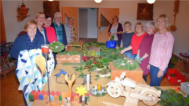 Hier stellen Frauen aus dem Basarteam gerade weihnachtliche Türkränze her. Ein kleiner Ausschnitt aus dem vielfältigen Basarangebot ist im Vordergrund zu sehen.