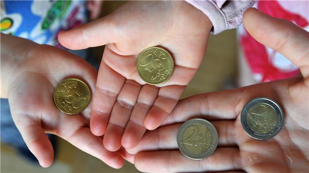 Drei Hände halten Geldstücke in die Kamera