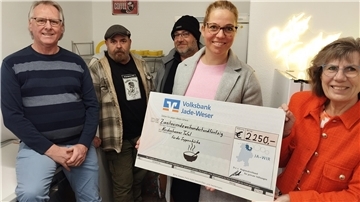 Zwei Männer und drei Frauen mit einem Scheck.