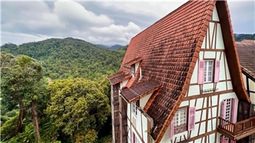 Hinter einem Fachwerkhaus in Colmar Tropicale ist der Dschungel der Berjaya Hills zu sehen.