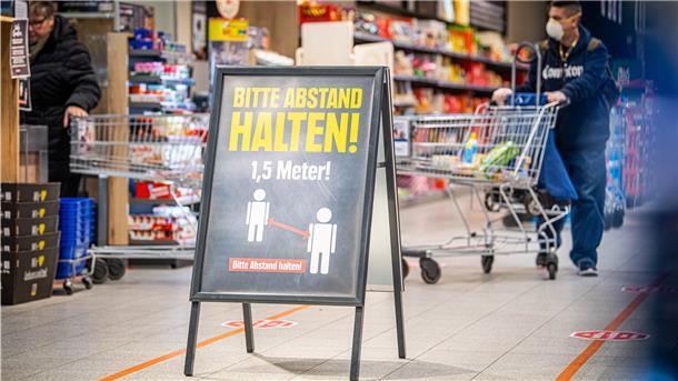 Hinweisschilder am Eingang und entlang der Kassen weisen die Kunden auf den nötigen Sicherheitsabstand hin. Supermärkte haben unterschiedliche Ansätze, das Einhalten der Abstände sicherzustellen.