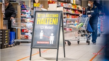 Hinweisschilder am Eingang und entlang der Kassen weisen die Kunden auf den nötigen Sicherheitsabstand hin. Supermärkte haben unterschiedliche Ansätze, das Einhalten der Abstände sicherzustellen.
