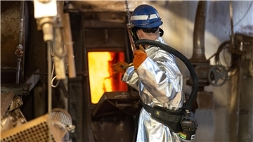 Arbeiter im Hitzeschutzanzug vor Ofen in Metallwerk, Glencore-Standort Nordenham