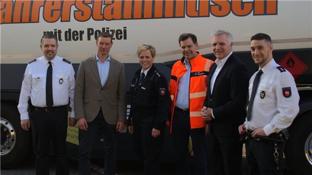 Fünf Männer und in der Bildmitte eine Frau stehen vor einem Lkw mit der Aufschrift "Fernfahrerstammtisch der Polizei".