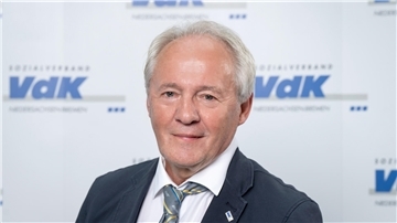 Mann mit grauen Haaren und Anzug mit Krawatte.