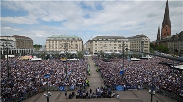 HSV-Fans stehen auf dem Rathausmarkt vor dem Hamburger Rathaus und feiern ihren Club.