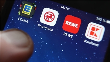 Icons der Apps von den Handelsketten wie Edeka, Rossmann und REWE auf dem Display eines iPhones.
