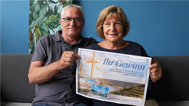 Überraschung auf dem Wasser: Bremerhavenerin gewinnt Kreuzfahrt Ein Mann und eine Frau halten einen Gutschein in der Hand.