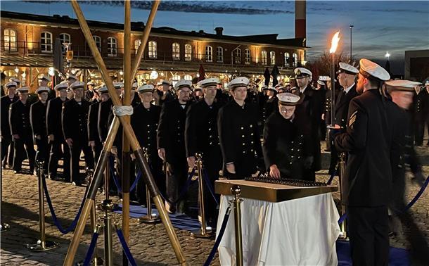 Eine Menschenschlange in schwarzen Uniformen und mit weißen Mützen im maritimen Stil. Die Personen greifen sich Coins.