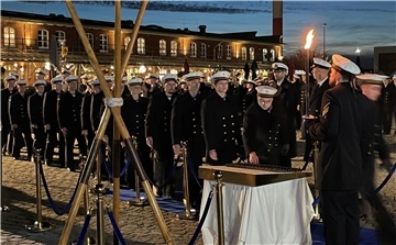 Eine Menschenschlange in schwarzen Uniformen und mit weißen Mützen im maritimen Stil. Die Personen greifen sich Coins.