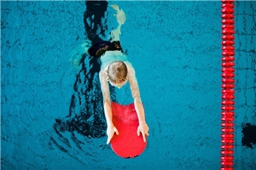 Das Foto zeigt, wie ein Kind das Schwimmen lernt. 