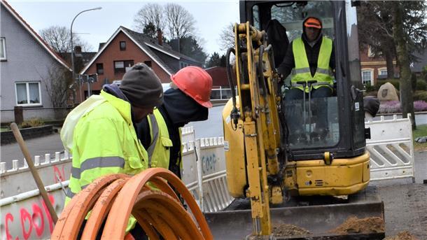 Mehrere Bauarbeiter verlegen ein Glasfaser-Kabel-