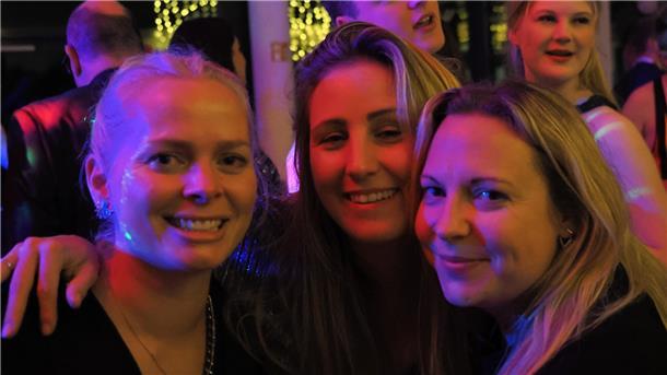 Drei Frauen lächeln in die Kamera.