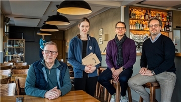 Rüdiger Magowsky, Merle Scheithauer, Tim Oberdieck und Christian von Rumohr sitzen in einem Bistro.