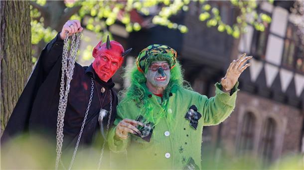 Im Hexen- und Teufelskostüm stehen zwei Walpurgis-Besucher in Wernigerode vor der Erstürmung des Rathauses im Stadtzentrum.