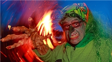 Im Hexenkostüm steht ein Besucher des Walpurgisfestes in Schierke am Feuer.