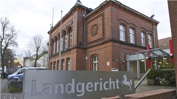 Ein Schild mit der Aufschrift "Landgericht" steht vor einem Gebäude. 