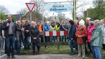 Eine Gruppe von Menschen in Waddens rund um ein stilisiertes Fahrrad aus VA-Stahl
