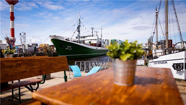 Was kann man in Bremerhaven machen? Tipps für den Besuch in der Stadt am Meer Ein Blick über einen Tisch auf Schiffe, die im Hafen liegen. Die Sonne scheint.