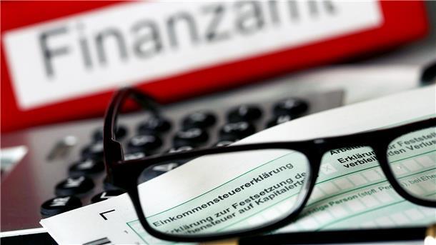 Rotenburg ist zweitlangsamstes Finanzamt in Niedersachsen Eine Brille liegt auf einem Formular für die Einkommenssteuererklärung. Beides liegt auf einer Tastatur. Im Hintergrund ist verschwommen das Wort "Finanzamt" zu erkennen.