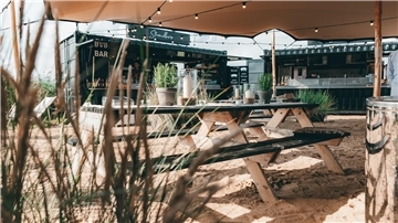 Zwei Container, aus denen Getränke und Essen verkauft wird, stehen an einem Strand.
