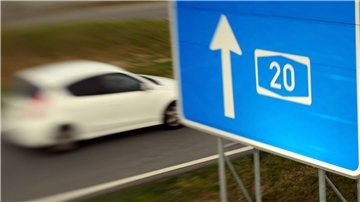 Ein Autobahnschild, an dem ein Auto vorbeifährt. 