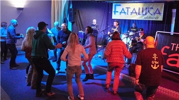 Menschen tanzen im Güterschuppen in Nordenham vor einer Bühne, auf der die Band Fatallica spielt.