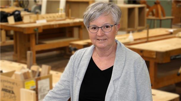 Eine Frau steht in einer Holzwerkstatt