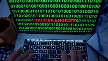 Ein aufgeklapptes Laptop mit dem Wort Hackerangriff auf dem Monitor.