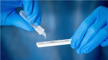 Medizinisch geschultes Personal träufelt nach dem Abstrich für einen Corona-Schnelltest in eine Lösung auf die Antigen-Testkasette.