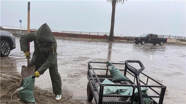 Tornados und Todesopfer nach Überschwemmungen in den USA In Aptos schaufelt eine Frau im strömenden Regen Sand in Säcke.
