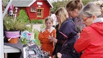 Mädchen und Frauen schauen sich an einem Stand im Abbehauser Osterdorf um.