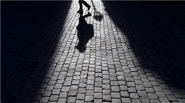  Der Schatten eines Fußgängers ist auf dem Pflaster zu sehen. 